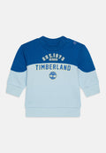 Hellblauer und dunkelblauer Sweatshirt mit langen Ärmeln. Mit "TIMBERLAND"-Logo und Grafik auf der Brust sowie Knopfdetails an der Schulter.