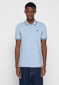 Mann trägt ein hellblaues Poloshirt mit kurzen Ärmeln, schwarzem Streifen an Kragen und Bündchen, schwarzem "HUGO"-Logo und dunkelblauer Jeans, steht mit gesenkten Armen.