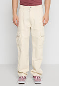 Cremefarbene Cargo-Hosen mit Seitentaschen, lockerer Passform, elastischen Bündchen und einem Metallknopfverschluss. Kombiniert mit rot-weiß karierten Slippern.