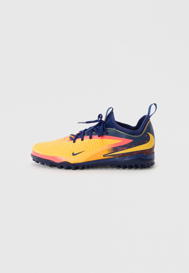 Der Sportschuh hat ein gelb und marineblaues Design, eine strukturierte Oberseite, kontrastierende pinkfarbene Akzente und eine dunkle Gummisohle mit Grip-Stollen.