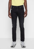 Schwarze Denim-Jeans mit schmalem Schnitt, Fünf-Taschen-Design, subtilen Nähtelementen und mittelhohem Bund, kombiniert mit grauen Sneakers.