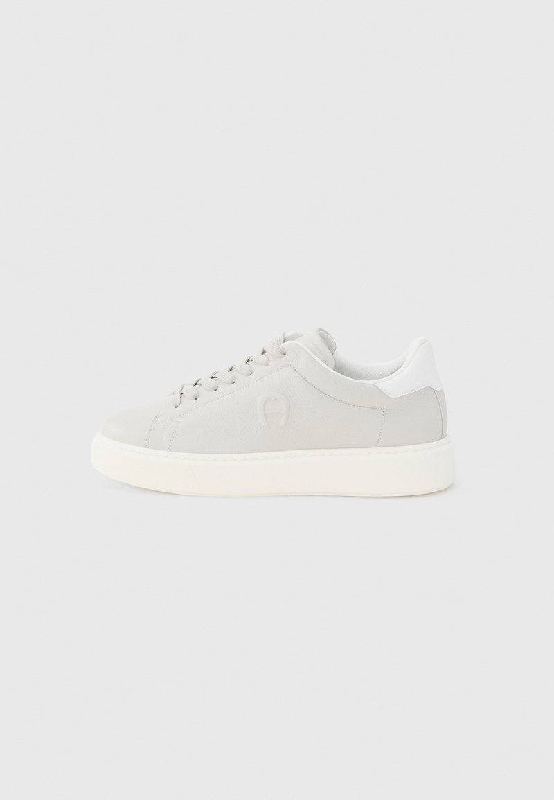 Niedriger hellgrauer Sneaker mit weißer Sohle, weißer Fersenschlaufe, Schnürsenkeln und subtil eingeprägtem Logo an der Seite, in rechter Seitenansicht gezeigt.
