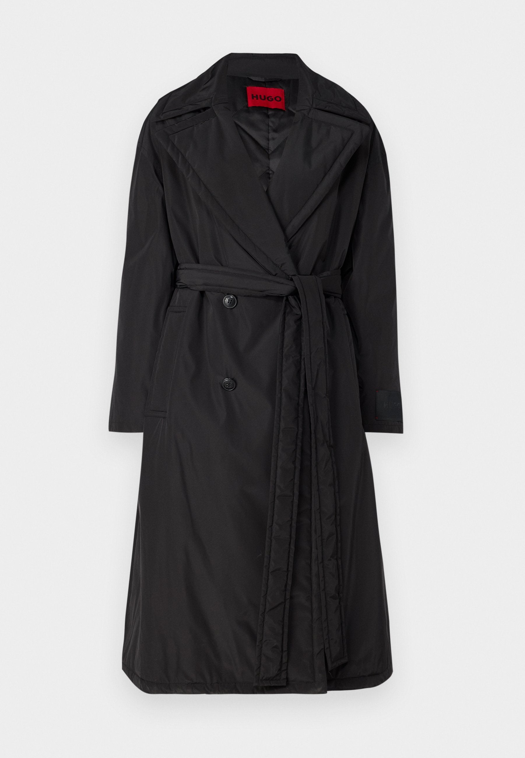 Schwarzer Trenchcoat mit Gürtel, aus glänzendem, leichtem Stoff gefertigt. Verfügt über große Knöpfe und einen eingekerbten Kragen. Mit dem Label "HUGO" in Rot.