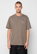 Braunes, kurzärmliges T-Shirt in lockerer Passform. Mit einem kleinen weißen Schriftlogo auf der linken Brust. Hergestellt aus weichem Baumwollmaterial.