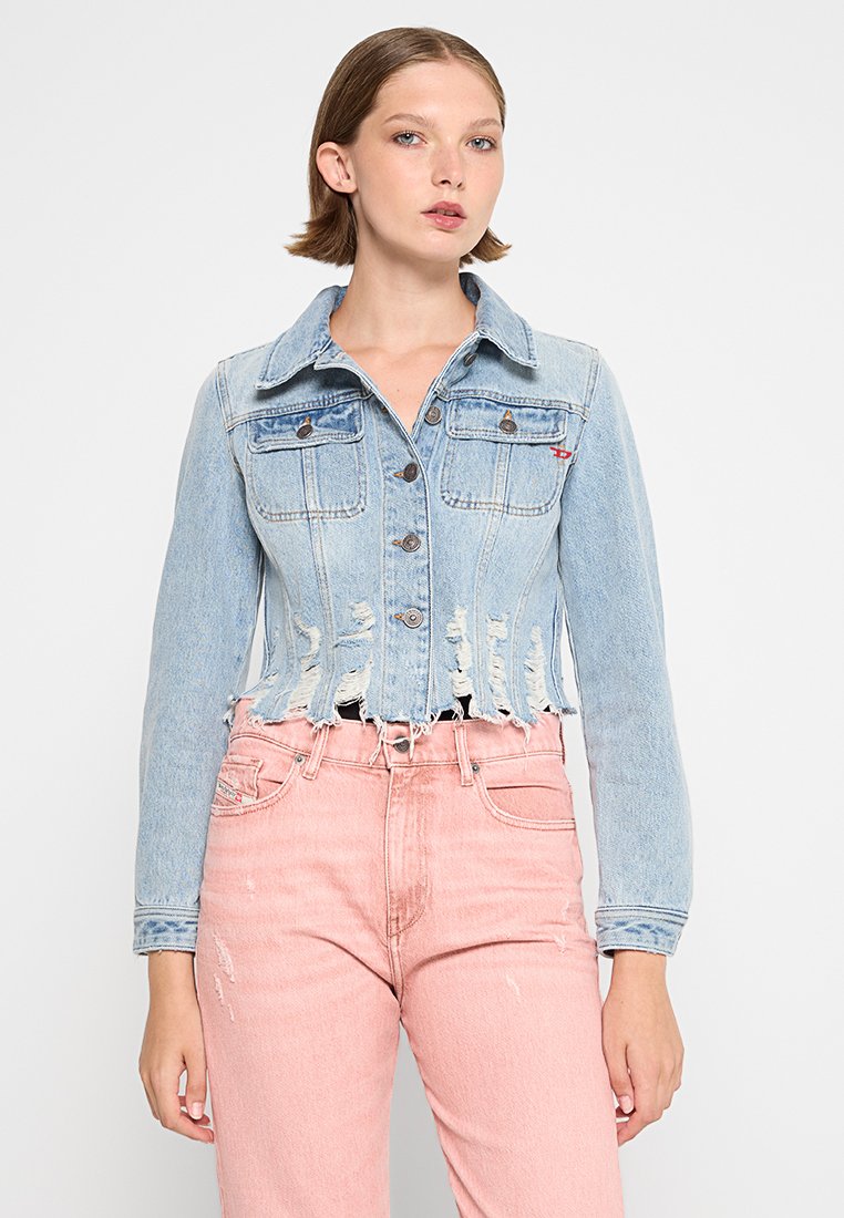 Hellblaues, cropped Denim-Jacke mit ausgefranstem Saum, Knopfleiste, zwei Brusttaschen und dezentem roten Logodetail. Getragen über rosa Jeans.