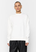 Weißes Sweatshirt mit Rundhalsausschnitt, langen Ärmeln und lässiger Passform, aus weichem Stoff; getragen über schwarzen Lederhosen.