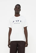 Mann trägt ein weißes T-Shirt mit schwarzen abstrakten Figuren und dem Schriftzug „PS Paul Smith“, kombiniert mit dunkelbrauner Hose, steht vor weißem Hintergrund.