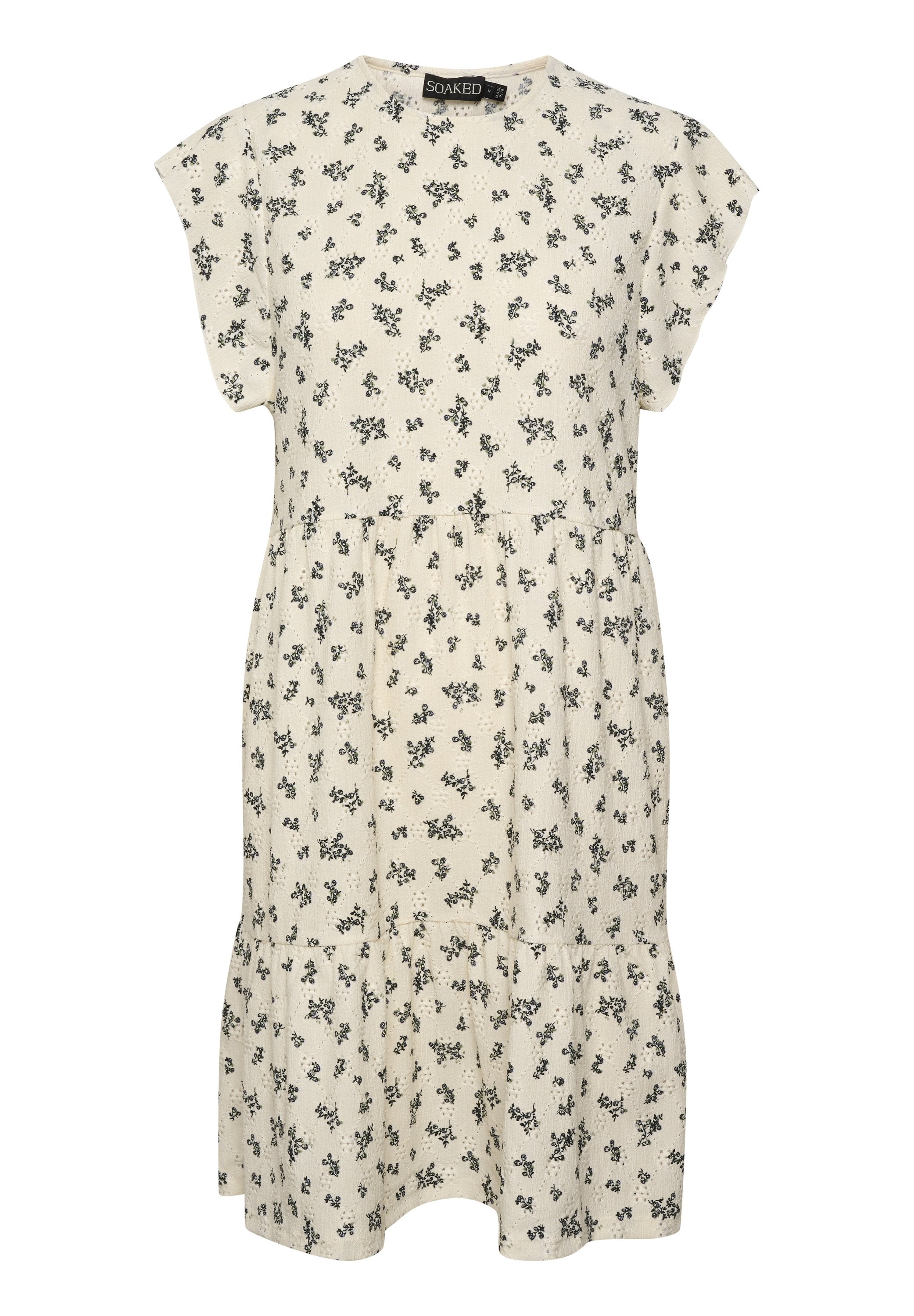 Kleid mit floralem Druck in Creme, mit kurzen Ärmeln, rundem Halsausschnitt und gestuftem Saum. Mit kleinen schwarzen Blumen, die gleichmäßig verteilt sind.
