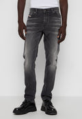 Graue Jeans aus Denim mit einem ausgewaschenen Finish, geradem Schnitt, fünf Taschen Design und einem kleinen Logo-Detail auf der vorderen Tasche. Getragen mit schwarzen Schuhen.