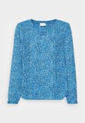Blaue Bluse mit langen Ärmeln, die ein florales Muster in Schwarz und Weiß zeigt, mit einem runden Halsauschnitt und leicht gerafften Ärmelabschlüssen. Leichter Stoff.
