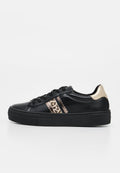 Schwarzer Sneaker mit niedrigem Schnitt, dicker Sohle, schwarzen Schnürsenkeln, metallisch goldener Ferse und Leopardenmuster mit gezacktem Rand am seitlichen Streifen.