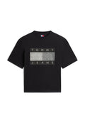 Schwarzes Baumwoll-T-Shirt mit einem rechteckigen Motiv, auf dem "TOMMY" und "JEANS" in Weiß vor einem strukturierten grauen Hintergrund zu sehen sind. Kurze Ärmel.