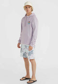 Lila Kapuzenpullover mit Fronttasche und Logopatch, kombiniert mit gemusterten pastellfarbenen Badeshorts mit Blattdesigns. Schwarze Flip-Flops runden das Outfit ab.