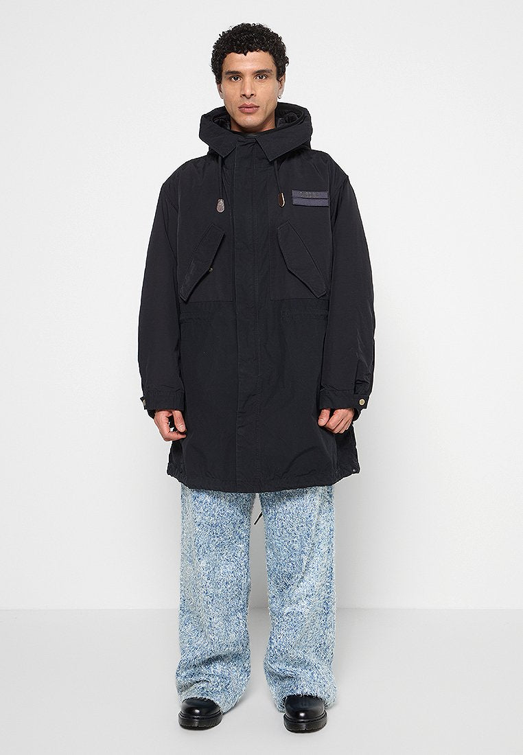 Schwarzer Parka mit Kapuze, großen Fronttaschen, einem Reißverschluss und dezenten lila Akzenten auf der Brust. Getragen über strukturierten blauen Hosen.