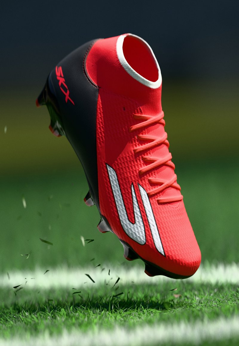 Roter und schwarzer Fußballschuh mit Schnürsenkeln, weißem Logo und Stollen, der Gras auf einem grünen Feld nahe einer weißen Linie aufwirbelt.