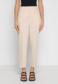 Beige maßgeschneiderte Hose mit hoher Taille, gefaltetem Frontbereich und geradem Bein. Glatter Stoff in neutraler Farbe für vielseitige Styling-Optionen. Schwarze Riemchensandalen.