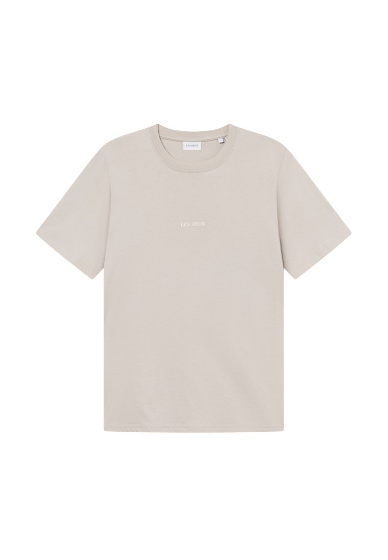 Beige Baumwoll-T-Shirt mit kurzen Ärmeln, rundem Halsausschnitt und dezentem 'LES DEUX'-Text in Weiß auf der Vorderseite. Glatte Textur.