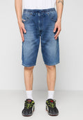 Mann in blauen Jeansshorts in Kniehöhe mit elastischem Bund und Kordelzug, weißen Socken und schwarzen Turnschuhen mit Neonakzenten, steht mit den Händen an den Seiten.