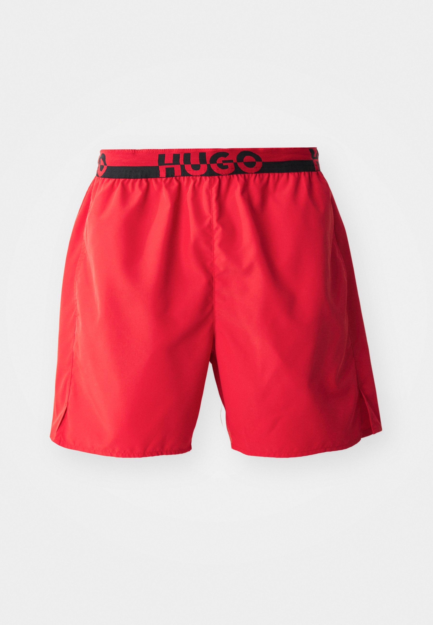 Rote Badeshorts aus leichtem Stoff, ausgestattet mit einem schwarzen elastischen Bund mit "HUGO"-Markierung und seitlichen Schlitzen für Bewegungsfreiheit.