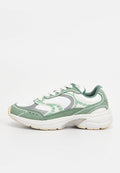 Weißer und grüner Sportschuh mit dicker Sohle, wellenförmigem Design, Schnürverschluss und "Tommy Jeans"-Markierung an der Ferse.