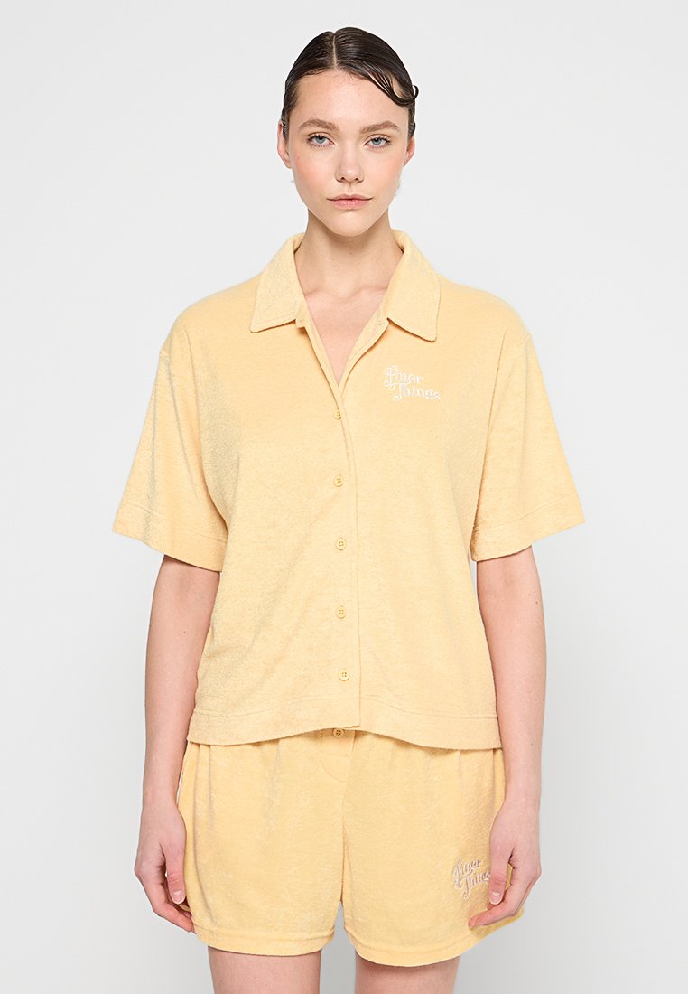 Kurzarmhemd mit Knöpfen und Shorts aus weichem gelbem Frottee, mit gesticktem Logo auf der linken Brust und dem Oberschenkel.