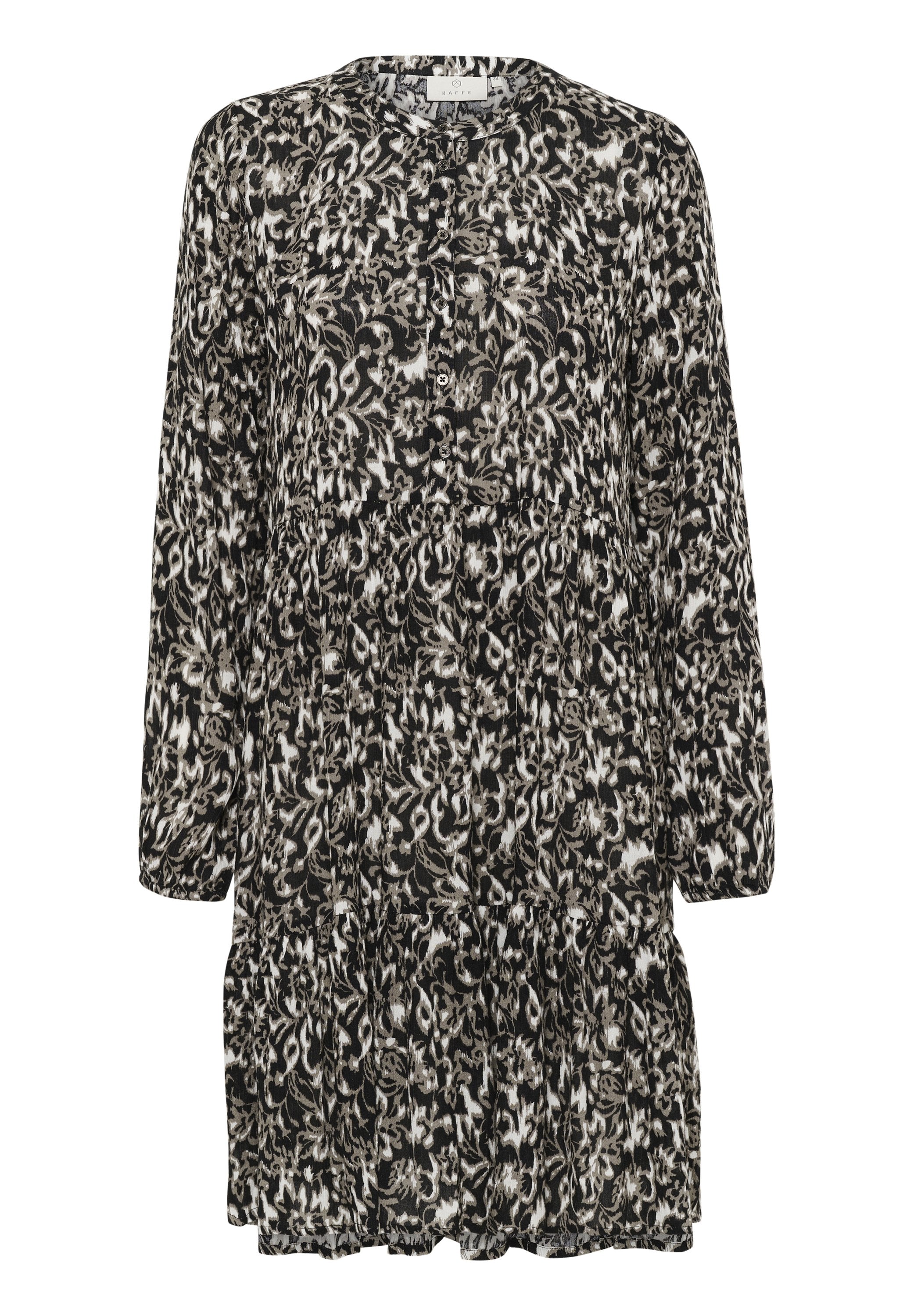 Schwarz-weiß gemustertes Kleid mit Rundhalsausschnitt, langen Ärmeln und Knopfdetails; der Volant am Saum sorgt für Struktur und Fülle.