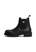 Schwarze Leder-Stiefelette mit dicker Sohle, elastischen Seiten, Schaffellfutter und Tommy Jeans-Logo an der äußeren Seite.