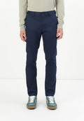 Marineblaue Chinos aus leichtem Material; mit schmaler Passform, Gürtelschlaufen, frontalen Taschen und Knopfverschluss. Kombiniert mit grünen Sneakern.
