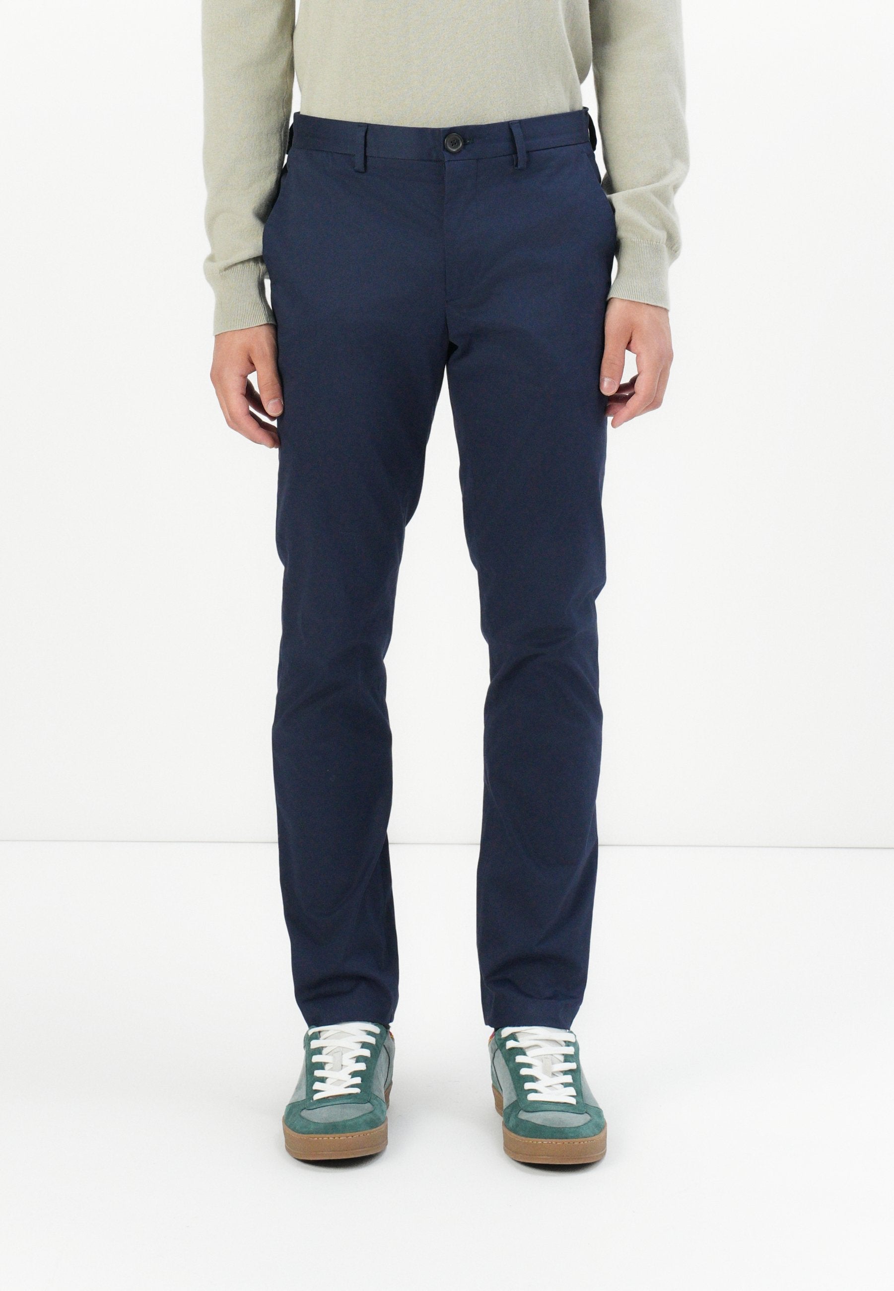 Marineblaue Chinos aus leichtem Material; mit schmaler Passform, Gürtelschlaufen, frontalen Taschen und Knopfverschluss. Kombiniert mit grünen Sneakern.
