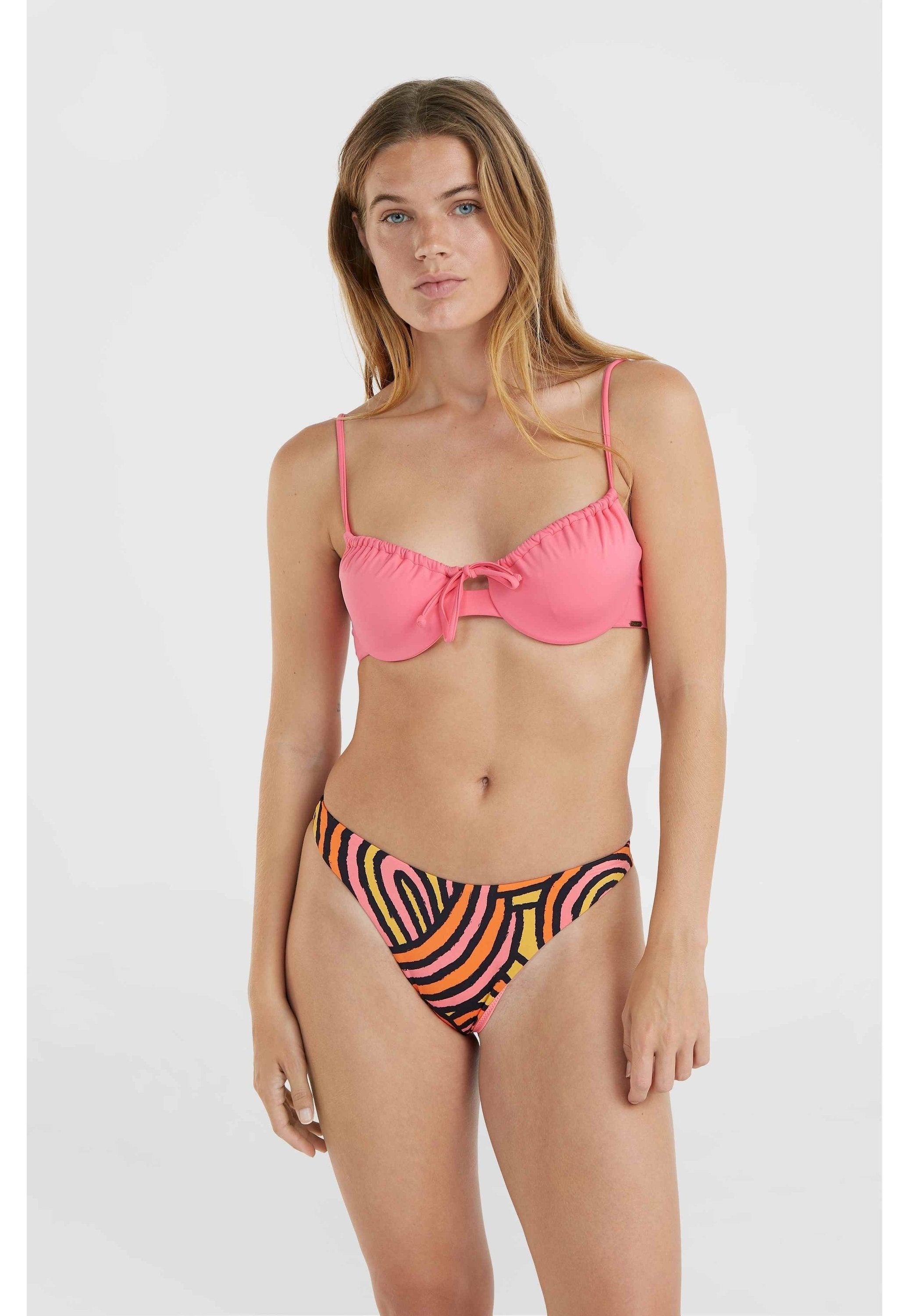 Rosa Bikini-Oberteil mit Rüschenrand und zentralem Bindedetail, kombiniert mit einem hochgeschnittenen Bikiniunterteil, das abstrakte Muster in Orange, Rosa und Schwarz zeigt.