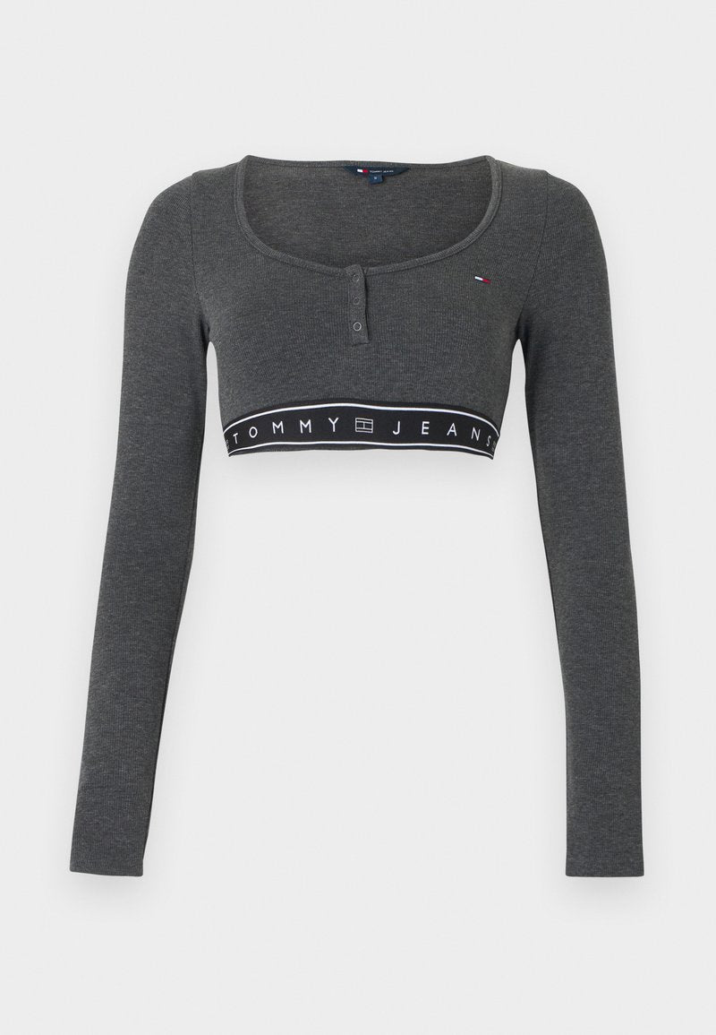 Graues langärmeliges kurzes Oberteil mit rundem Ausschnitt, Knopfleiste und einem schwarzen Band mit der Aufschrift "TOMMY JEANS". Weiche Stoffstruktur.