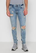 Helle blaue, schmale Jeans mit ausgefransten Löchern an den Knien und Oberschenkeln, aus Denim. Getragen mit grauen Sportschuhen.