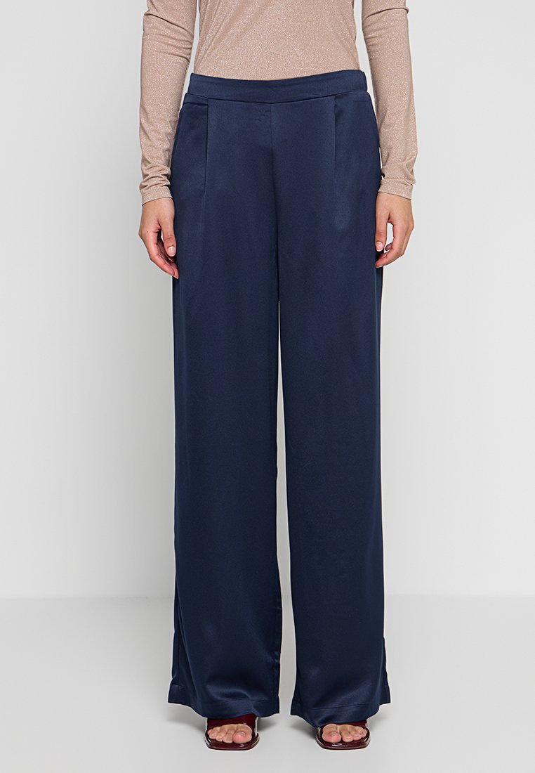 Marineblaue Hosen mit weitem Bein aus glattem Stoff, mit flacher Vorderseite, seitlichen Taschen und einer taillierten Passform für einen entspannten Sitz.