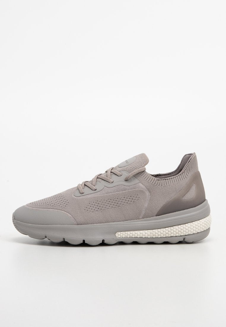 Grauer Sportschuh mit Obermaterial aus strukturiertem Strick, Gummisohle und hellgrauen Schäumelementen. Besitzt eine gepolsterte Ferse zur Unterstützung.