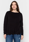 Schwarzer, langärmliger Strickpullover mit weitem Ausschnitt und lockerer Passform, ausgestattet mit gerippten Bündchen und Saum. Kombiniert mit hellblauen, faded Jeans.