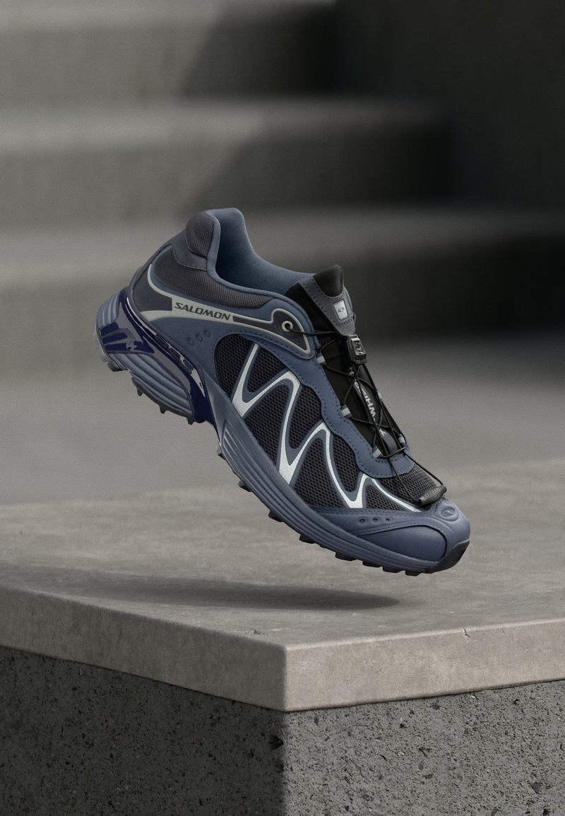 Salomon Trailrunning-Schuh mit einem Obermaterial aus Mesh in Marineblau und Grau, einem Schnellschnürverschluss und einer strukturierten Gummisohle.