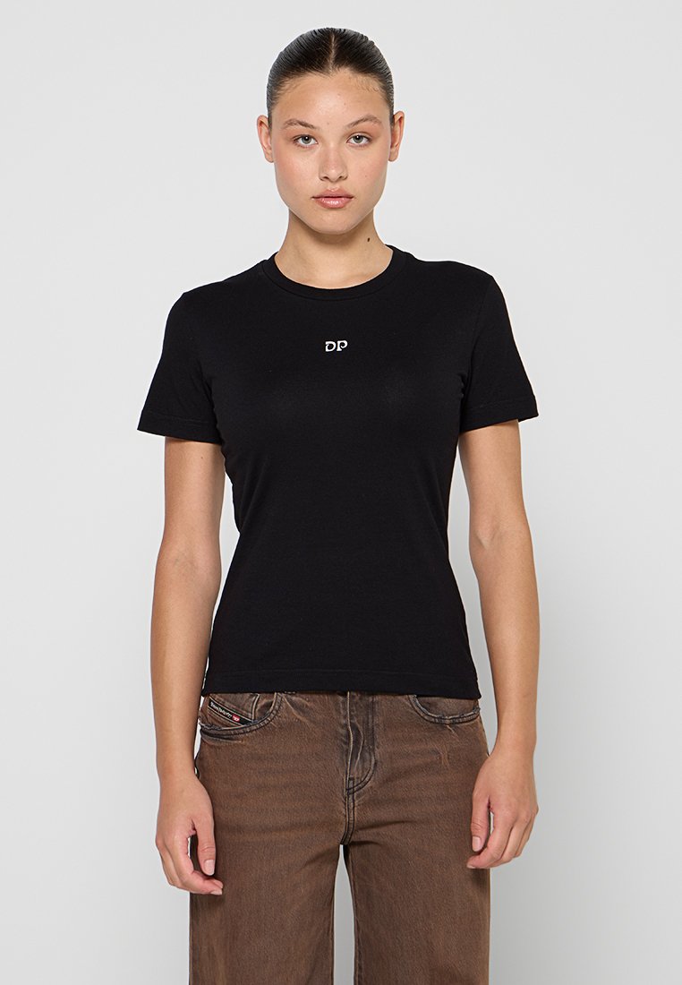 Schwarzes Baumwoll-T-Shirt mit Rundhalsausschnitt und kurzen Ärmeln, mit einem kleinen weißen "DP"-Logo auf der Brust. Das Modell trägt braune Hosen.