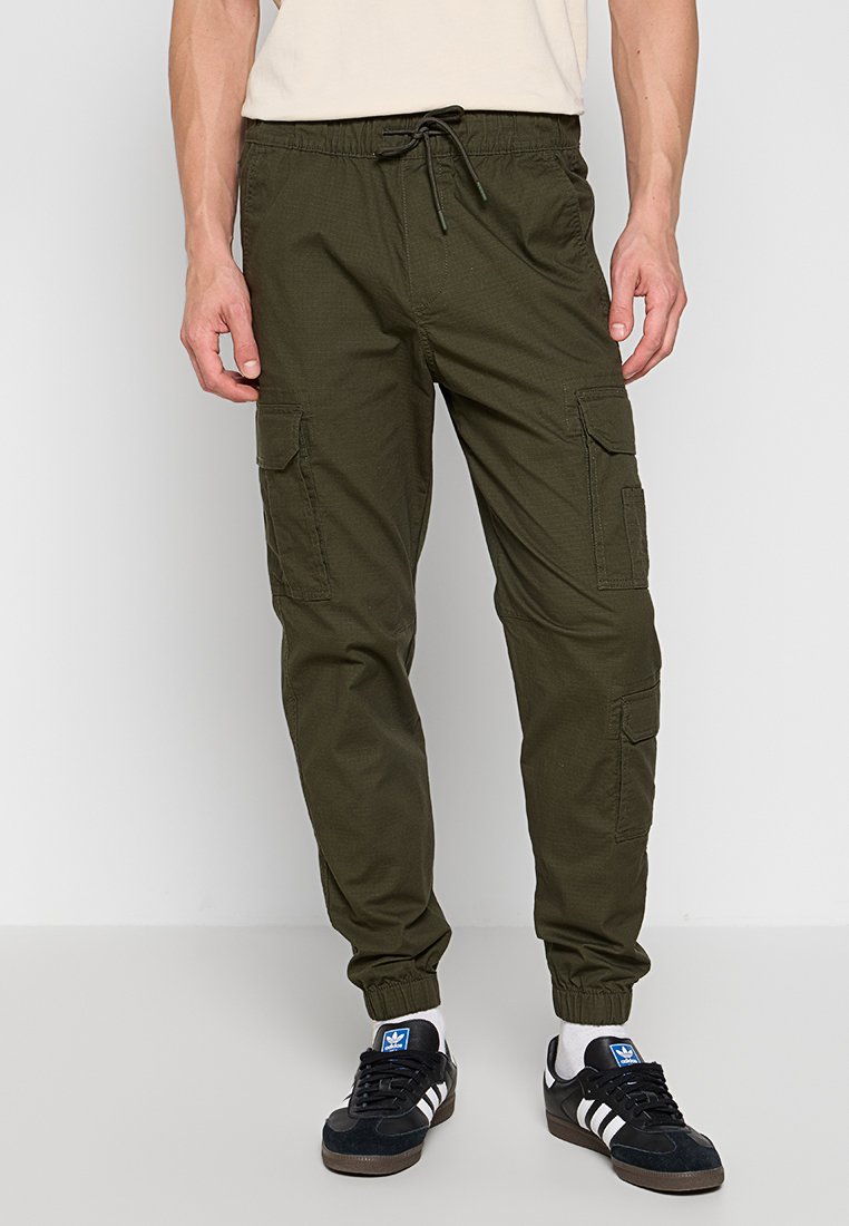 Olivenfarbene Cargo-Hosen mit elastischen Bündchen, Kordelzugbund und mehreren seitlichen Taschen. Aus leichtem Stoff gefertigt, der für Komfort sorgt.