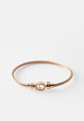Armband aus verdrehtem Roségolddraht mit einem kleinen, pferdegebissförmigen Verschluss, verziert mit klaren Kristallen auf weißem Hintergrund.