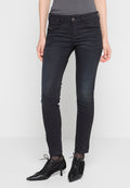 Person in schmalen schwarzen Jeans, schwarzen spitzen Schnürschuhen mit Kitten-Heels und einem grauen Oberteil, stehend vor einem schlichten Hintergrund.