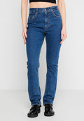 Person trägt hoch taillierte, blaue gerade Jeans und schwarze klobige Loafer, ein kurzes schwarzes Oberteil ist über der Taille sichtbar.