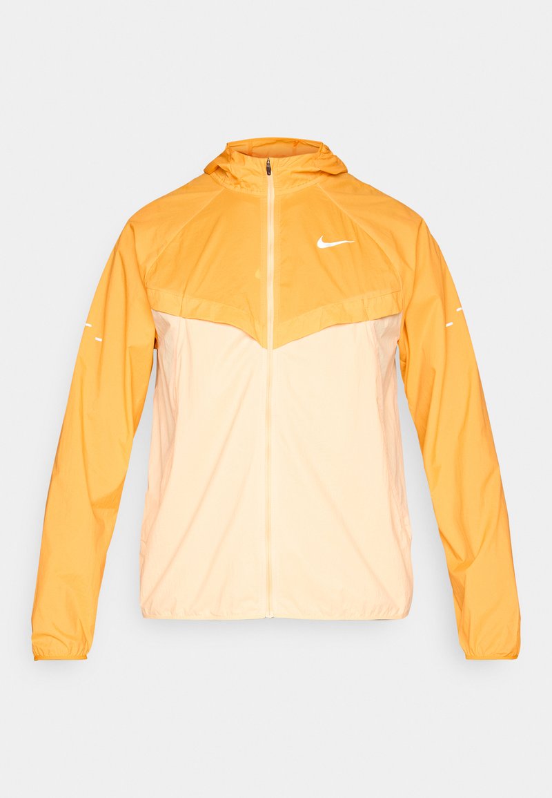 Hellorange und cremefarbene Nike Windjacke mit Kapuze, Frontreißverschluss und weißem Swoosh-Logo auf Brust und Ärmeln.