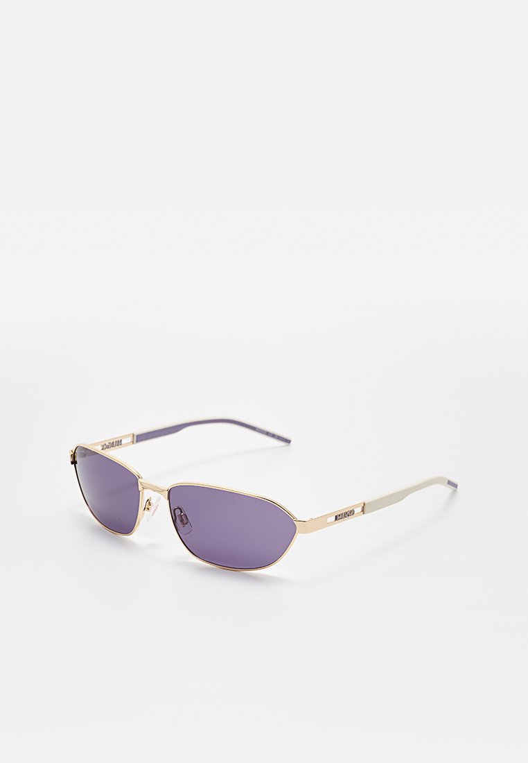 Rechteckige, violett getönte Sonnenbrille mit dünnem goldfarbenem Metallgestell und weißen Bügeln, liegend auf einer weißen Oberfläche.
