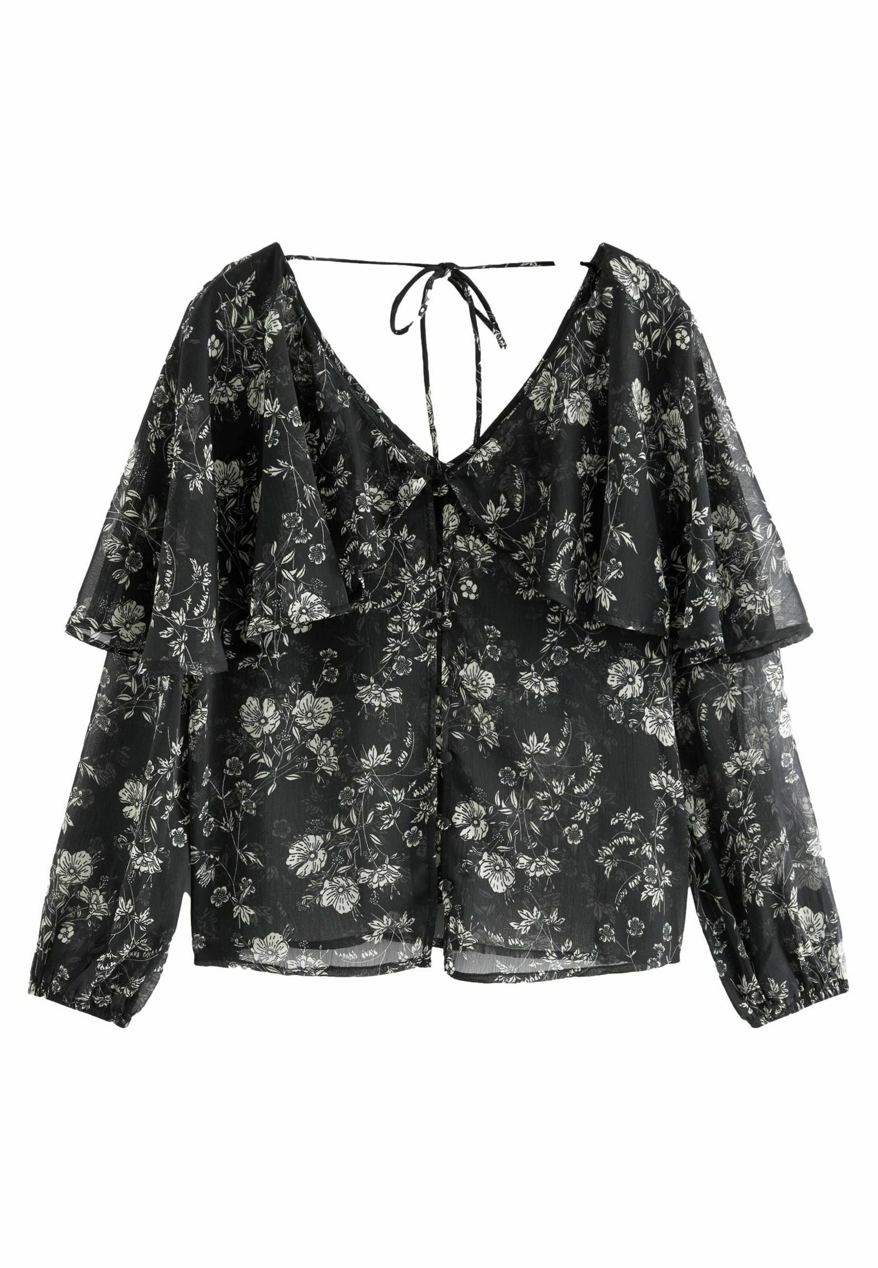 Schwarze Bluse mit floralem Muster, V-Ausschnitt, Rüscheln an den Ärmeln und einer Schleife im Rücken. Hat weiße Blumenmuster auf dem durchscheinenden Stoff.