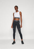 Weißes ärmelloses Crop-Top mit schwarzem "NIKE PRO"-Bund, kombiniert mit schwarzen Leggings, die das "NIKE PRO"-Logo und strukturierte Akzente aufweisen. Schwarze Sportschuhe.