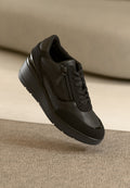 Schwarze Sneakers aus strukturiertem Leder und Mesh, mit einem seitlichen Reißverschluss, Schnürung vorne und einer leicht erhöhten Gummisohle.