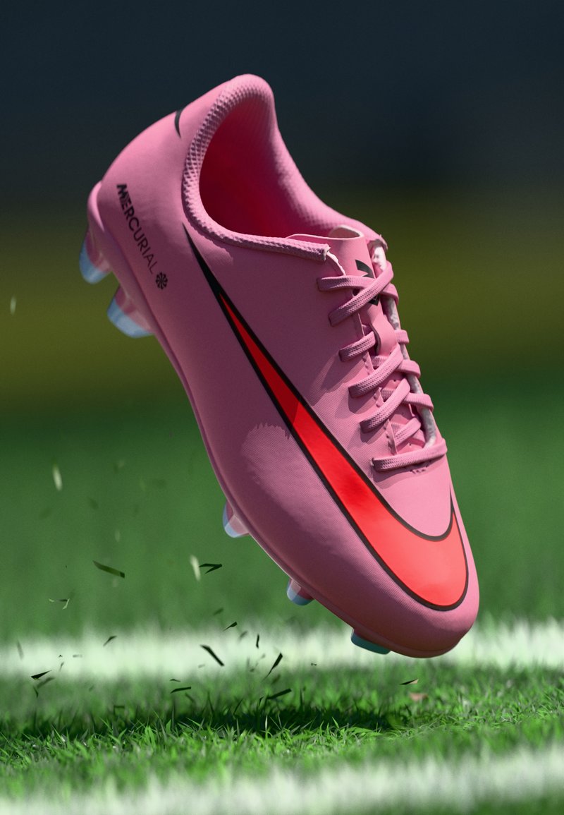 Nike Mercurial Fußballschuh in Pink mit einem auffälligen schwarzen und roten Swoosh, ausgestattet mit einer strukturierten Oberseite und klaren Stollen auf einer grasbewachsenen Fläche.