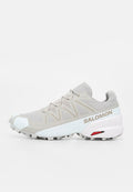 Hellgrauer und weißer Salomon Trailrunning-Schuh mit Mesh-Obermaterial, schützendem Zehenschutz, robuster Sohle und „Salomon“-Logo an der Seite.