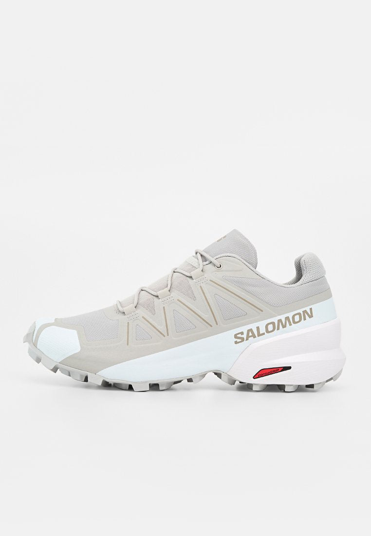 Hellgrauer und weißer Salomon Trailrunning-Schuh mit Mesh-Obermaterial, schützendem Zehenschutz, robuster Sohle und „Salomon“-Logo an der Seite.
