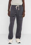 Person in dunkelgrauen Cargo-Sweatpants mit Kordelzug und beigen Sneakers vor einem schlichten Hintergrund.